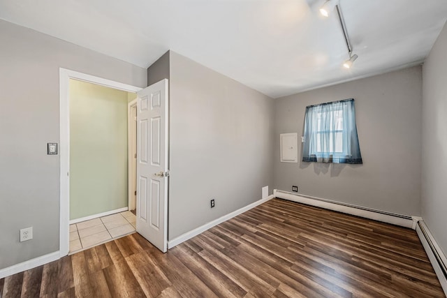 empty room with hardwood / wood-style floors, rail lighting, and baseboard heating