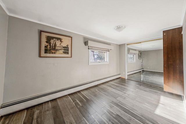 spare room with wood-type flooring, crown molding, and baseboard heating