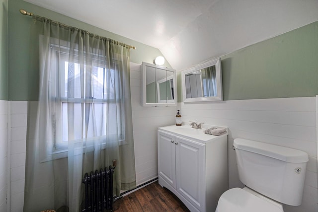 bathroom with radiator, wood-type flooring, lofted ceiling, vanity, and toilet