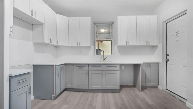 kitchen with gray cabinetry, sink, and light hardwood / wood-style floors