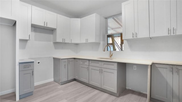 kitchen featuring light hardwood / wood-style floors, gray cabinets, sink, and backsplash