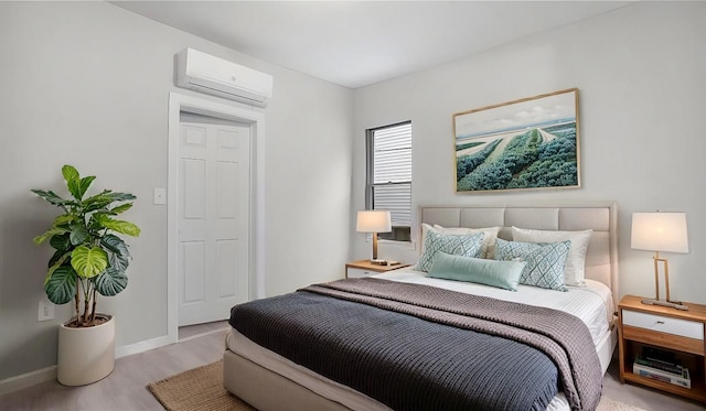 bedroom featuring an AC wall unit and light hardwood / wood-style floors