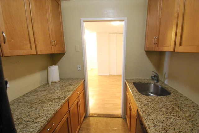 kitchen with light stone counters, sink, and light wood-type flooring