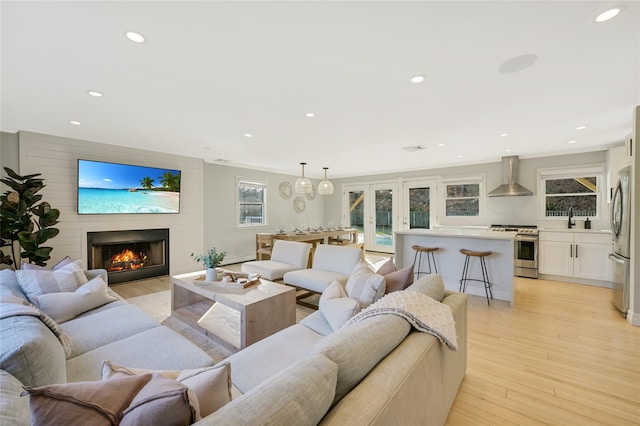 living room with french doors, a fireplace, and light wood-type flooring