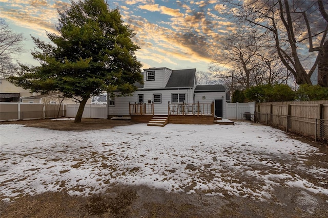 snow covered rear of property with a wooden deck