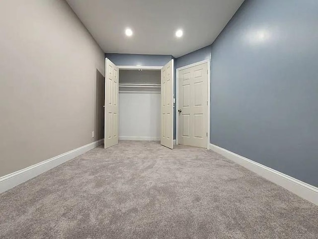 unfurnished bedroom with light colored carpet and a closet