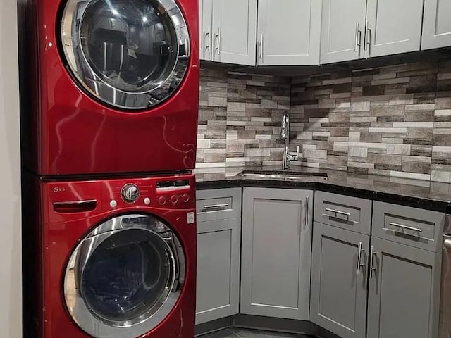 laundry area featuring cabinets, stacked washer and clothes dryer, and indoor wet bar