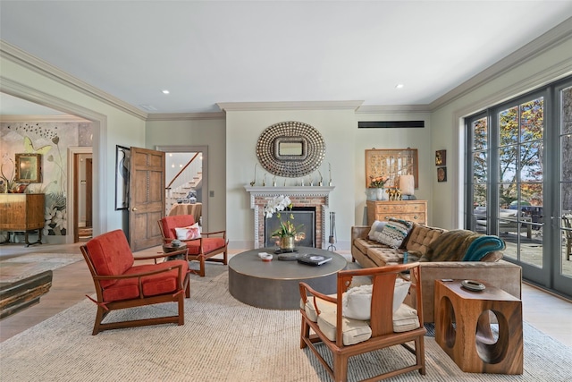 living room with crown molding, a brick fireplace, and light hardwood / wood-style flooring