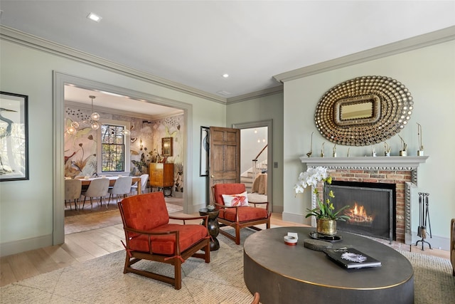 living area with crown molding, a fireplace, light hardwood / wood-style flooring, and a notable chandelier