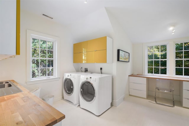 laundry area with cabinets, washer and dryer, and sink