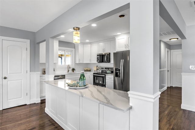 kitchen featuring light stone counters, dark hardwood / wood-style floors, kitchen peninsula, stainless steel appliances, and white cabinets