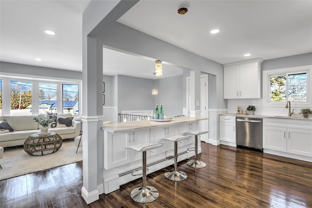 kitchen with a breakfast bar area, baseboard heating, white cabinets, dark hardwood / wood-style flooring, and stainless steel dishwasher