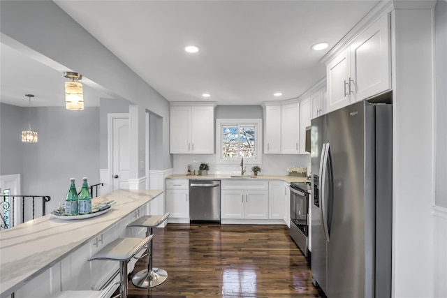 kitchen featuring white cabinetry, sink, hanging light fixtures, light stone counters, and stainless steel appliances