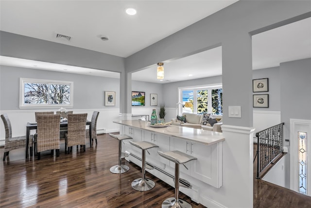 kitchen featuring dark hardwood / wood-style floors, white cabinetry, a kitchen breakfast bar, and a baseboard radiator