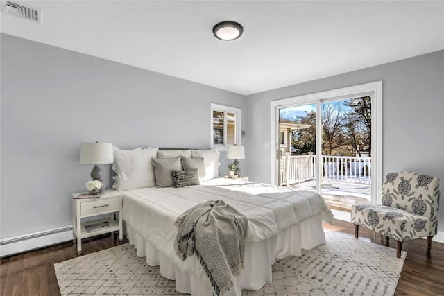 bedroom featuring baseboard heating, dark hardwood / wood-style floors, and access to exterior