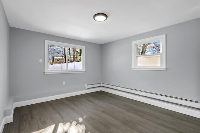 empty room with dark hardwood / wood-style flooring and a baseboard heating unit