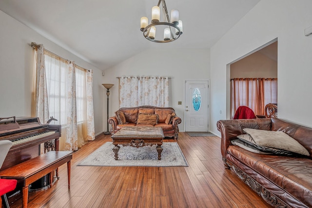 living room featuring an inviting chandelier, lofted ceiling, and light hardwood / wood-style flooring