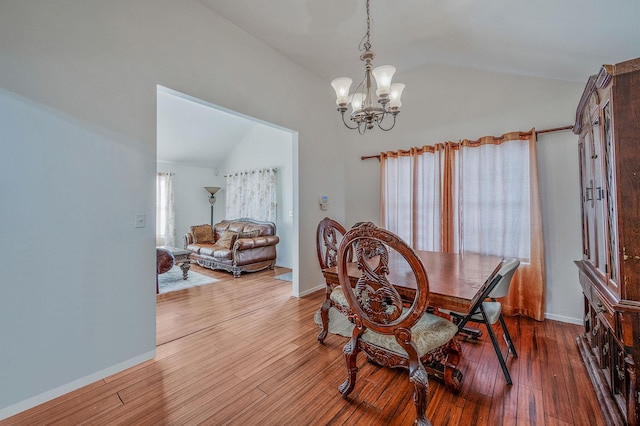 dining area with vaulted ceiling, hardwood / wood-style floors, and a chandelier