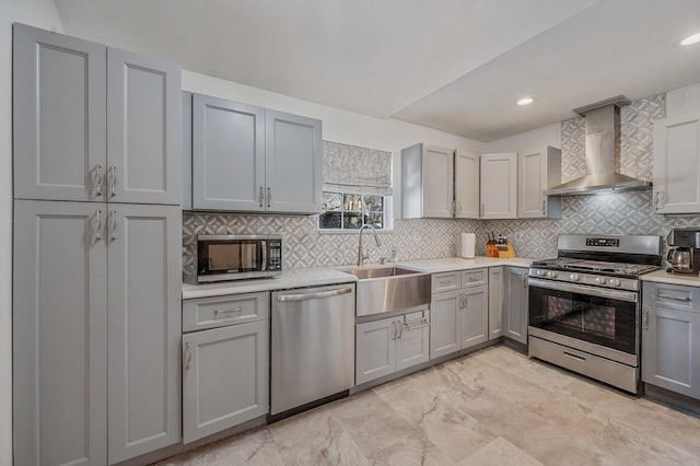 kitchen featuring gray cabinets, appliances with stainless steel finishes, tasteful backsplash, sink, and wall chimney range hood