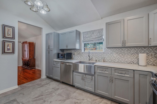 kitchen featuring gray cabinets, vaulted ceiling, appliances with stainless steel finishes, sink, and backsplash