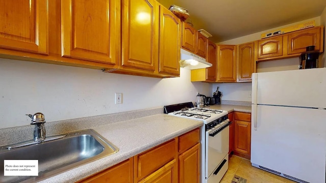 kitchen featuring white appliances, a sink, light countertops, under cabinet range hood, and brown cabinets