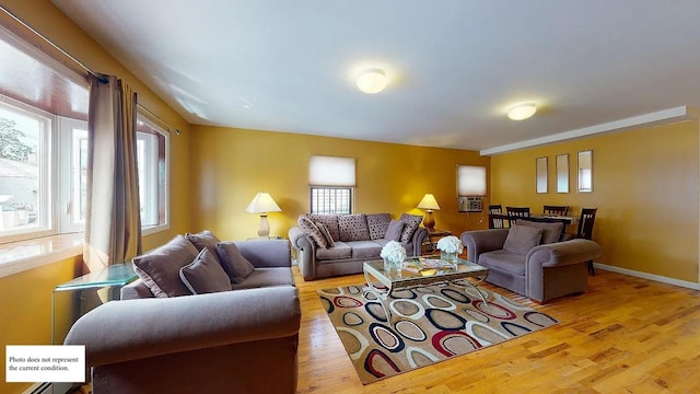 living room with cooling unit, baseboards, and wood finished floors