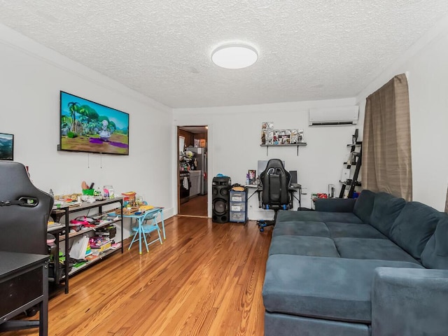 living room with hardwood / wood-style floors, a wall mounted AC, and a textured ceiling