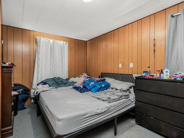 carpeted bedroom featuring wood walls