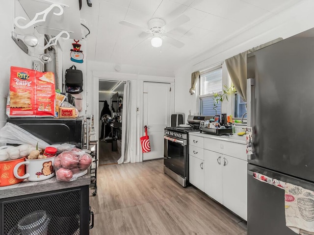 kitchen with appliances with stainless steel finishes, white cabinets, ceiling fan, and light hardwood / wood-style flooring