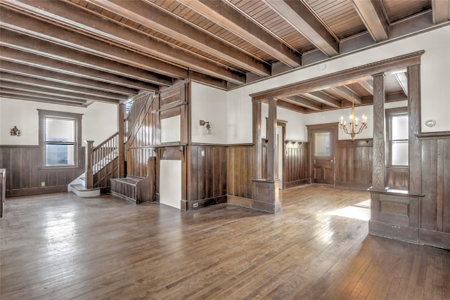 unfurnished living room with an inviting chandelier, wood ceiling, wood-type flooring, and beamed ceiling