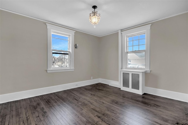 unfurnished room featuring crown molding, dark wood-type flooring, and an inviting chandelier