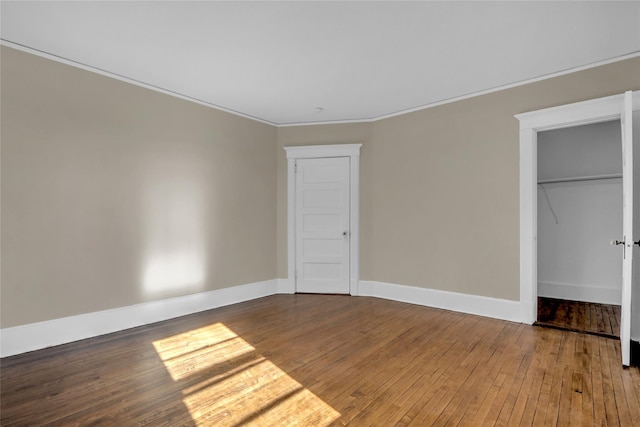 unfurnished bedroom with hardwood / wood-style floors, crown molding, and a closet