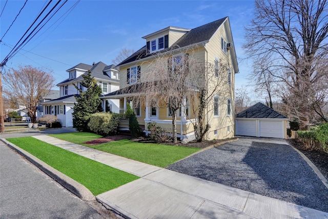 traditional style home with a detached garage, an outbuilding, covered porch, and a front yard