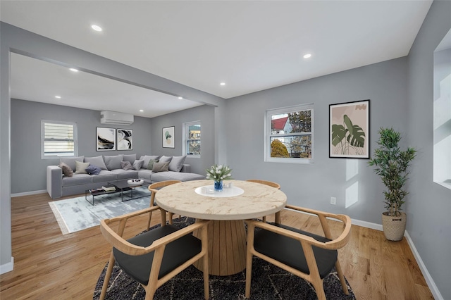 dining area with an AC wall unit and light hardwood / wood-style floors