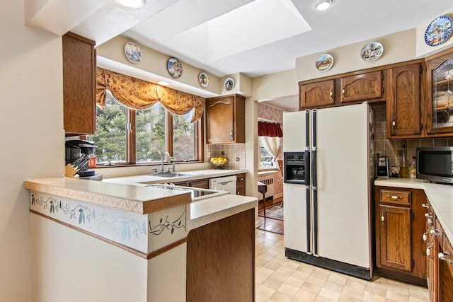 kitchen featuring white appliances, radiator, sink, and backsplash