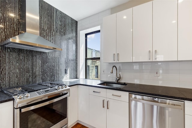 kitchen with white cabinetry, sink, decorative backsplash, stainless steel appliances, and wall chimney range hood