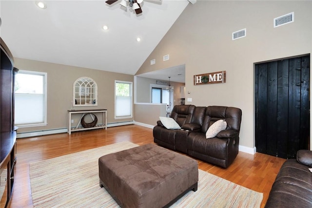 living room featuring baseboard heating, wood finished floors, visible vents, and baseboards