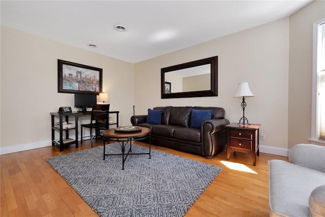 living area featuring wood finished floors, visible vents, and baseboards