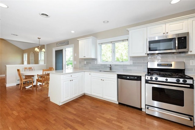 kitchen with a peninsula, visible vents, stainless steel appliances, and light countertops