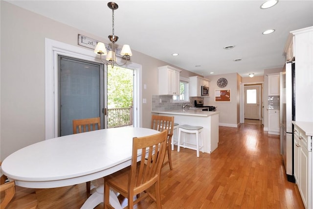 dining area with light wood-type flooring, a notable chandelier, baseboards, and recessed lighting