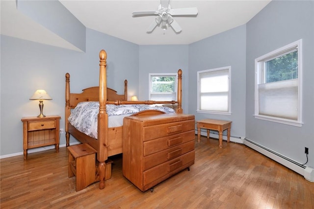 bedroom with light wood finished floors, baseboard heating, a baseboard radiator, and baseboards