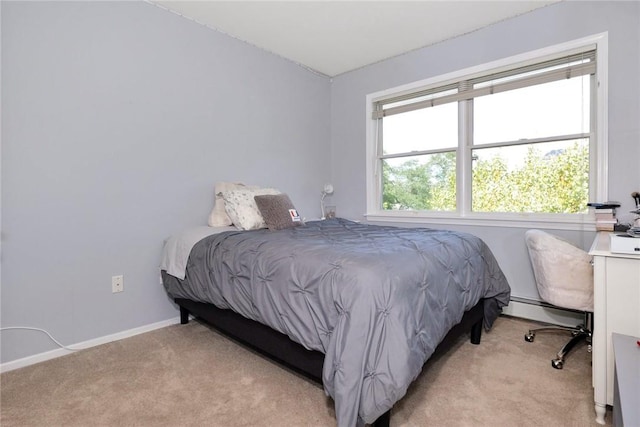 bedroom featuring light carpet, baseboard heating, and baseboards