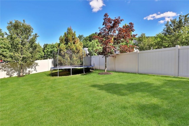 view of yard featuring a trampoline and a fenced backyard