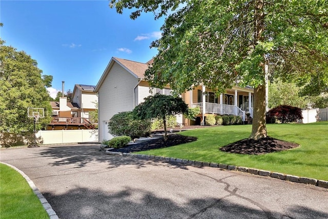 view of front of house featuring driveway, a porch, a front yard, and fence