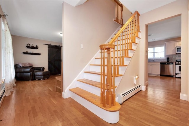 stairs featuring a baseboard heating unit, wood finished floors, baseboards, and a barn door