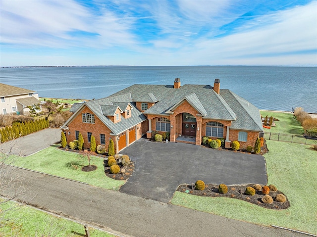 view of front of property featuring a water view, fence, aphalt driveway, and brick siding