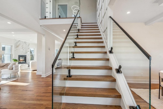 staircase featuring hardwood / wood-style flooring, a fireplace, and beamed ceiling