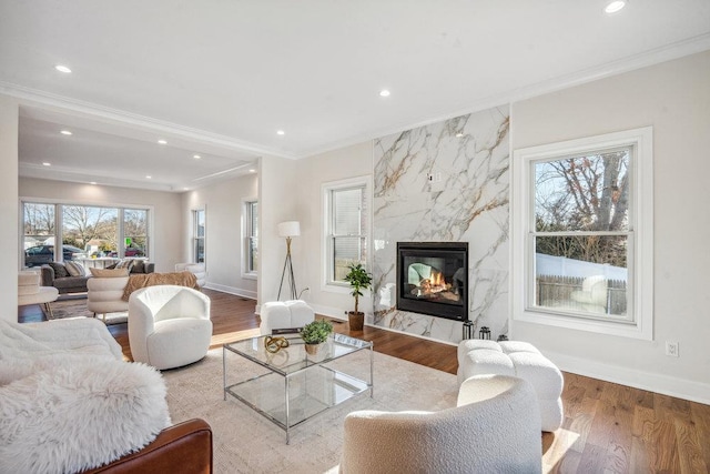 living room featuring hardwood / wood-style flooring, a premium fireplace, a wealth of natural light, and crown molding