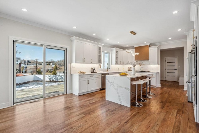 kitchen featuring white cabinetry, a kitchen breakfast bar, light stone countertops, a kitchen island, and decorative light fixtures