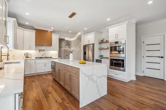 kitchen with sink, white cabinetry, stainless steel appliances, a center island, and light stone counters